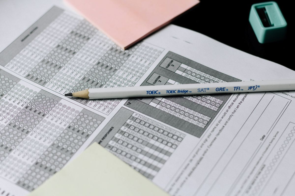 A person's hand with a pencil filling out answers on an English exam sheet, showing he has the expected CEFR level for TOEFL